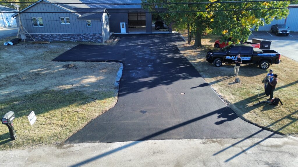 Freshly paved asphalt driveway with H&H Paving truck